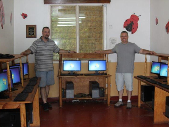 In this picture, two employees pose in front of a new computer lab built for students at the Treasures of Africa Children’s Home in Tanzania.