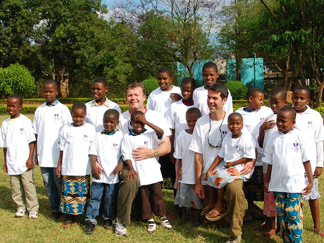 In this picture, an employee poses in a group shot with children at Treasures of Africa in Tanzania.